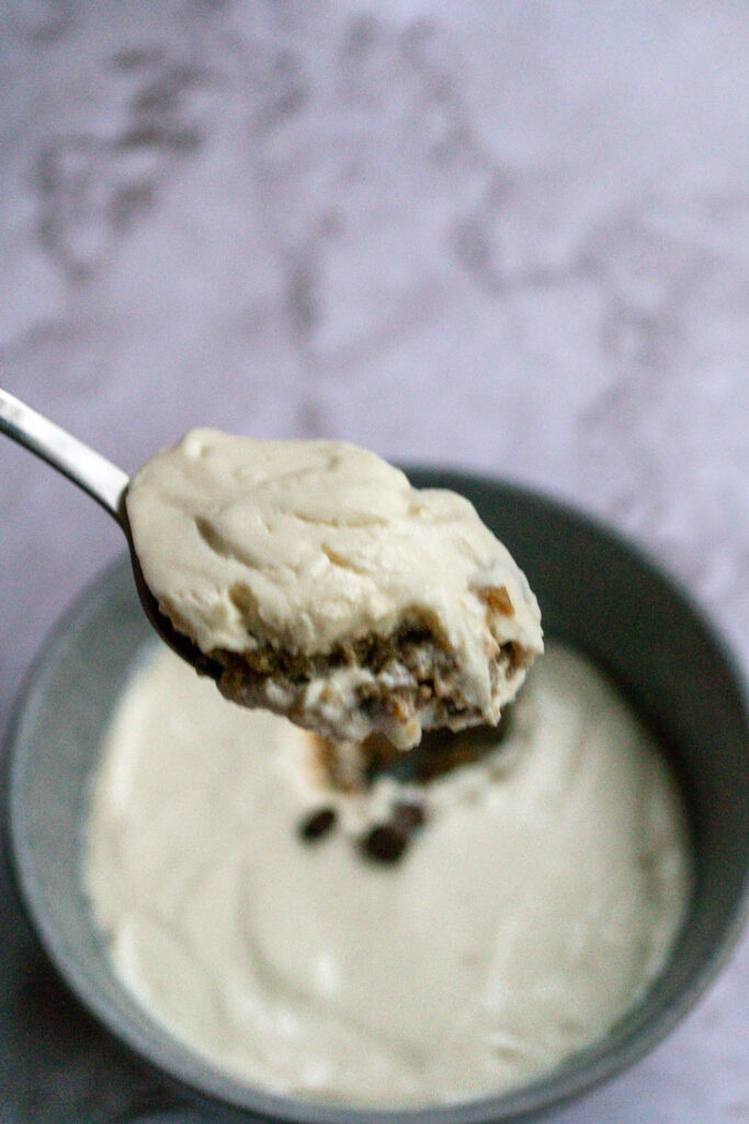 A bite of overnight weetabix on a spoon with a bowl of it in the background.