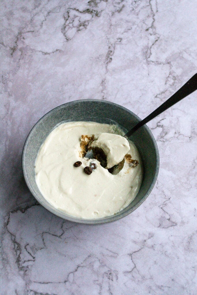 A bowl of caramel latte overnight weetabix in a grey bowl on a mable table.