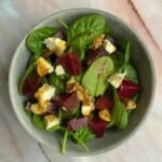 Rich green spinach leaves with roasted beet cubes, crumbled feta cheese, and toasted walnuts, creating a vibrant and healthy salad perfect for a nutritious meal.