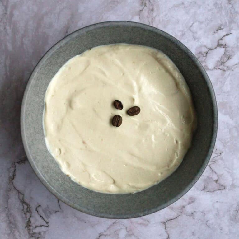 Creamy vanilla coffee pudding topped with three coffee beans, served in a gray bowl on a marble surface. Perfect for coffee-flavored desserts or a sweet treat.