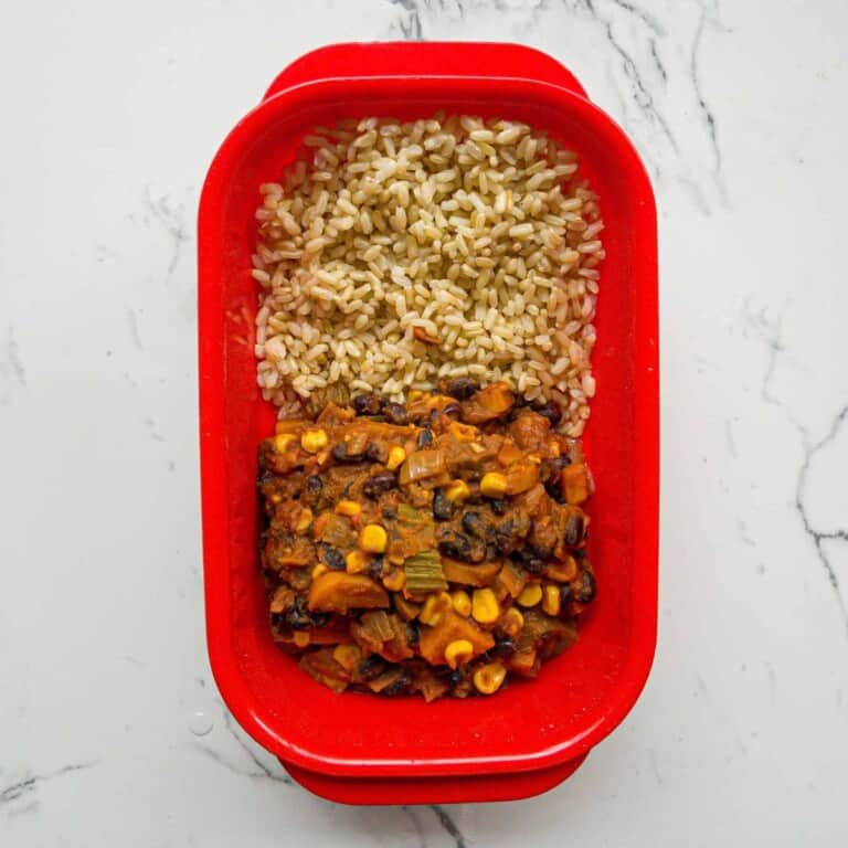 Sweet potato and black bean chili with rice meal prep in a red container, healthy vegetarian dinner, plant-based protein source, easy meal for lunch or dinner, gluten-free and vegan friendly.