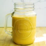 Creamy yellow smoothie in a glass jar with handle, fresh and healthy, perfect for breakfast or snack, featuring natural ingredients and vibrant color.