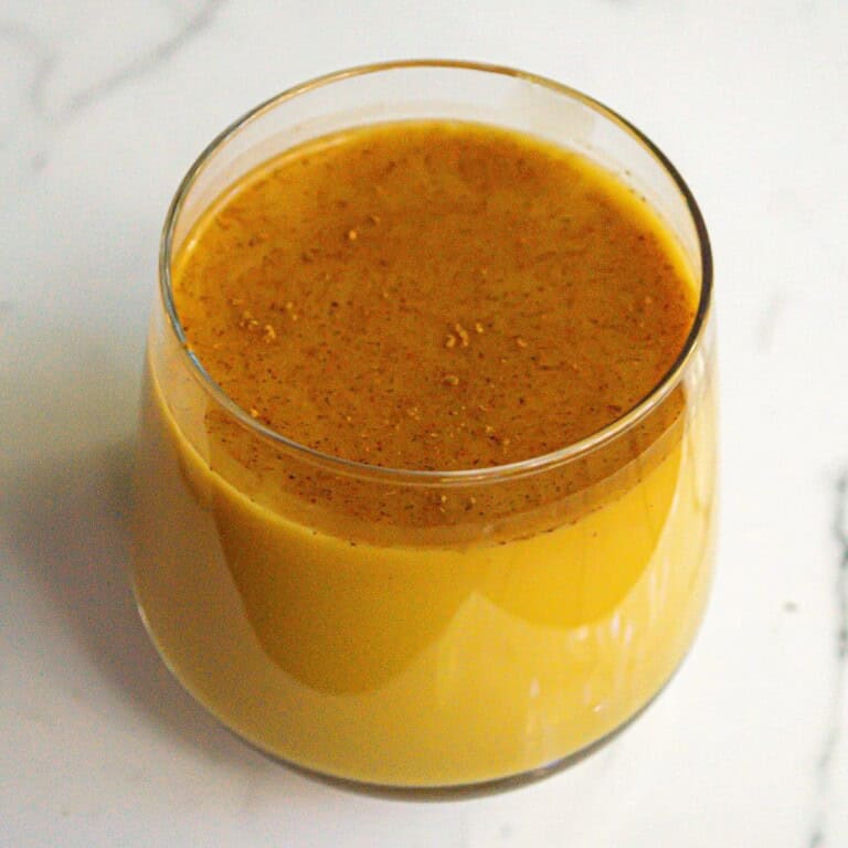 Creamy turmeric golden milk latte in a clear glass with a frothy surface, perfect for health and wellness. Rich in anti-inflammatory spices, ideal for cozy mornings or evening relaxation.