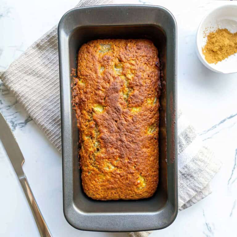 Golden baked meatloaf in a baking pan with seasoning salt on the side, served as a comforting homemade dinner.