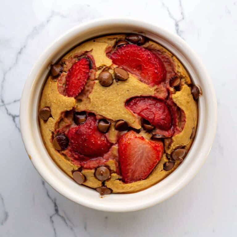 Fresh strawberry and chocolate chip baked dessert in a white ramekin, featuring a golden-brown crust and vibrant red fruit pieces. Perfect for healthy, delicious treats or breakfast options.