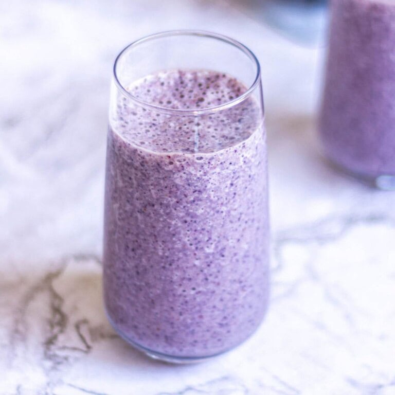 Creamy blueberry chia seed smoothie in a clear glass, showcasing vibrant purple color and textured surface, perfect for a healthy breakfast or snack.