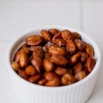 Roasted salted almonds in white ramekin, close-up of snack or healthy food option, salted nuts, high-quality photo.