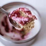 Creamy strawberry oatmeal pie filling in a spoon with a pink berry sauce swirl, served in a jar. Perfect for a healthy breakfast or dessert, featuring fresh strawberries and hearty oats.