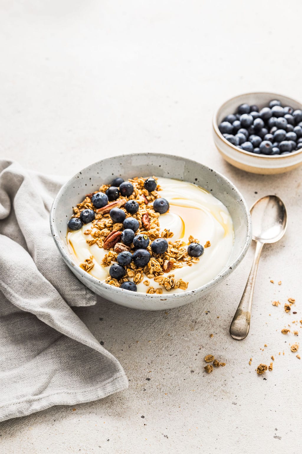 front view of vegan soy yogurt in a grey bowl, topped with blueberries and granola.