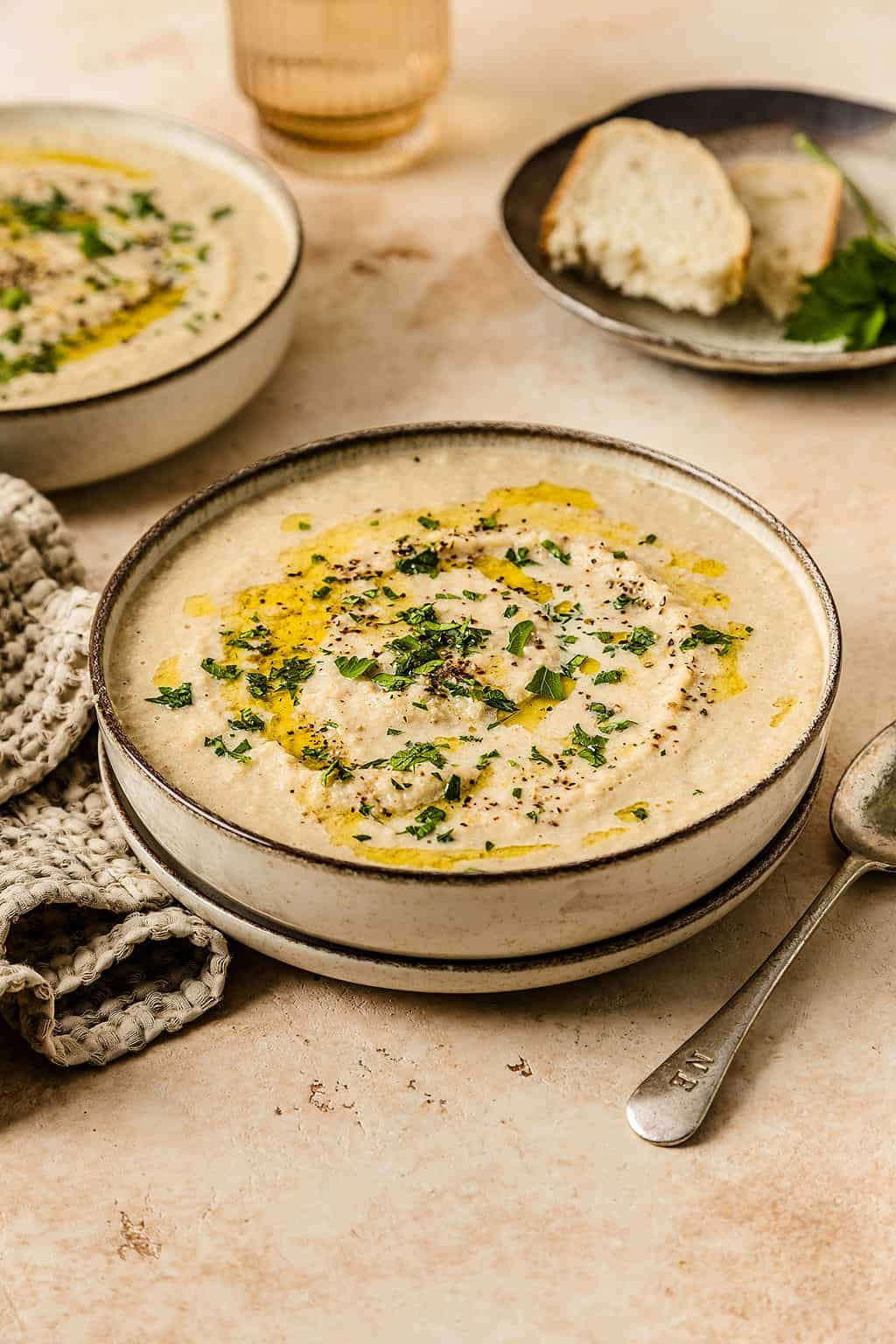 Front view of creamy cauliflower soup with a drizzle of olive oil and some parsley leaves on top.