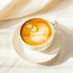 Oat milk coffee latte with latte art heart design in a white cup on white saucer, perfect for coffee lovers, vegan dairy-free alternative, healthy coffee beverage, simple and delicious coffee drinks.