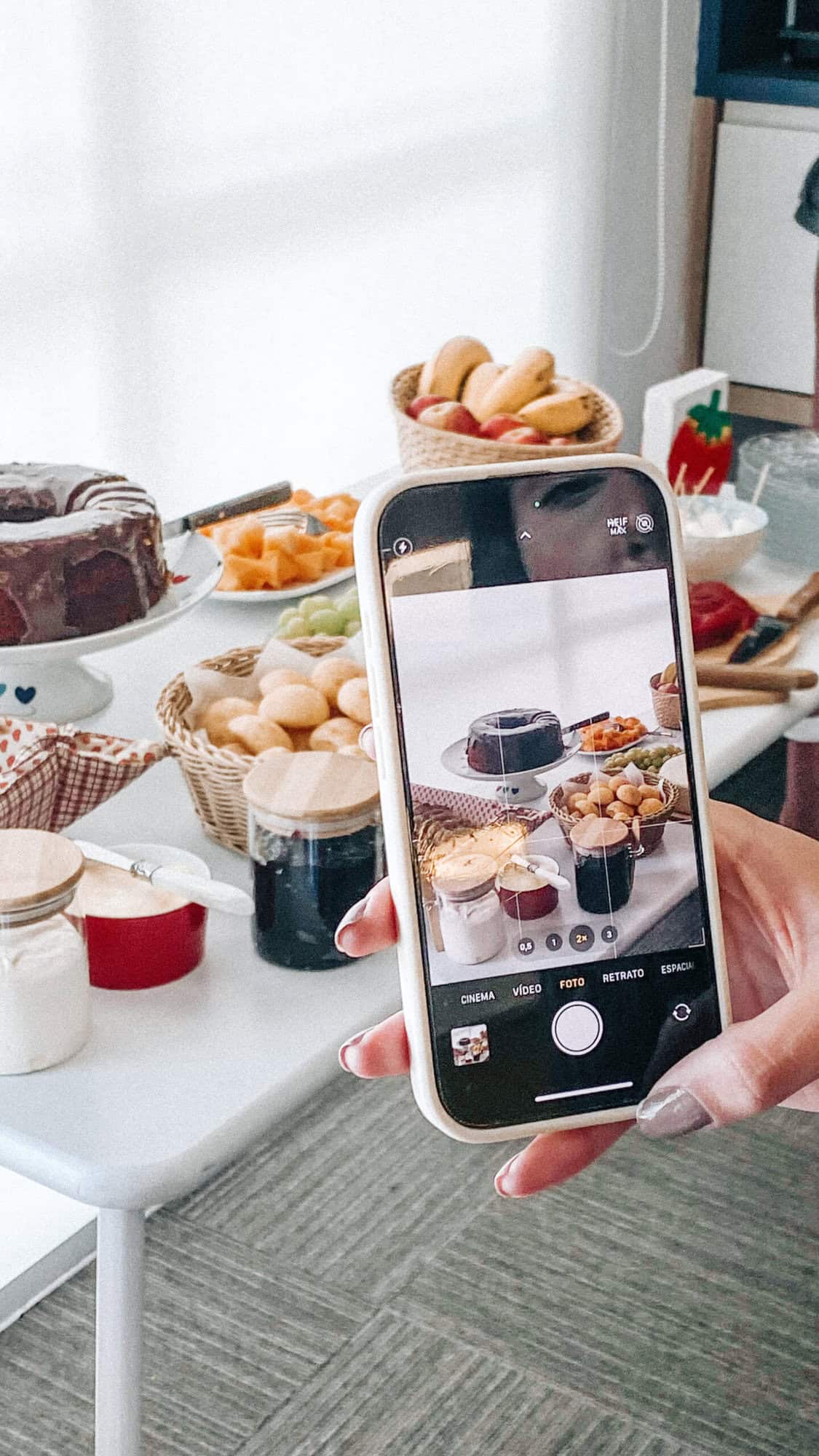 iPhone photographing fresh homemade desserts with fruit, chocolate, and baked goods for a cosy gathering.