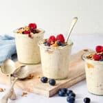 Creamy yogurt parfait with fresh berries, granola, and honey in glass cups on a wooden board - healthy breakfast or snack idea.
