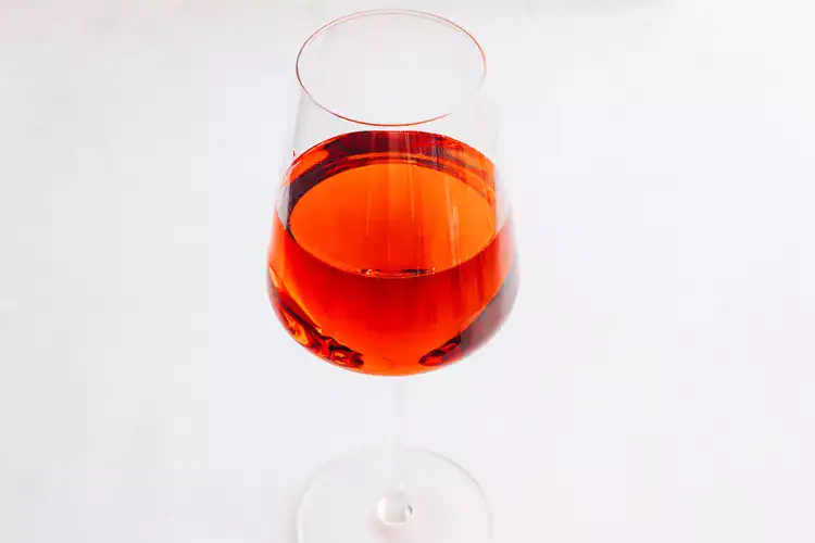 Red-coloured Kir cocktail served in a wine glass.