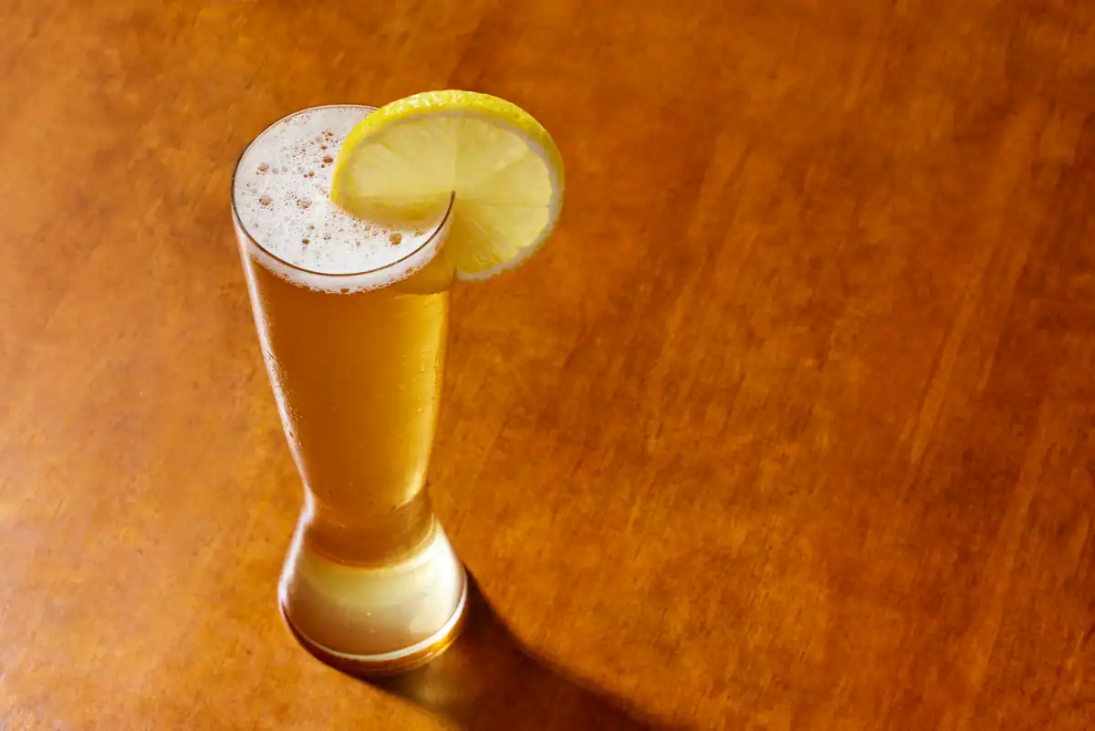 Shandy served in a tall beer glass with a slice of lemon.
