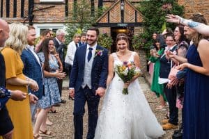 Bride and groom walking together after wedding ceremony surrounded by guests outdoors