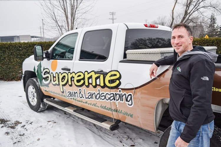 Supreme Lawn truck with landscaping logo and team member outdoors in winter scene.