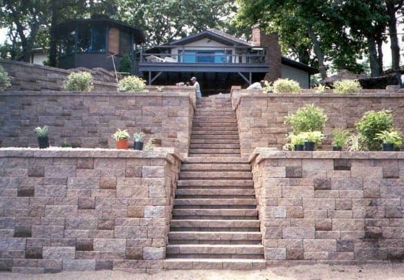Elegant stone retaining wall with landscaped garden and stairs, enhancing outdoor living spaces.