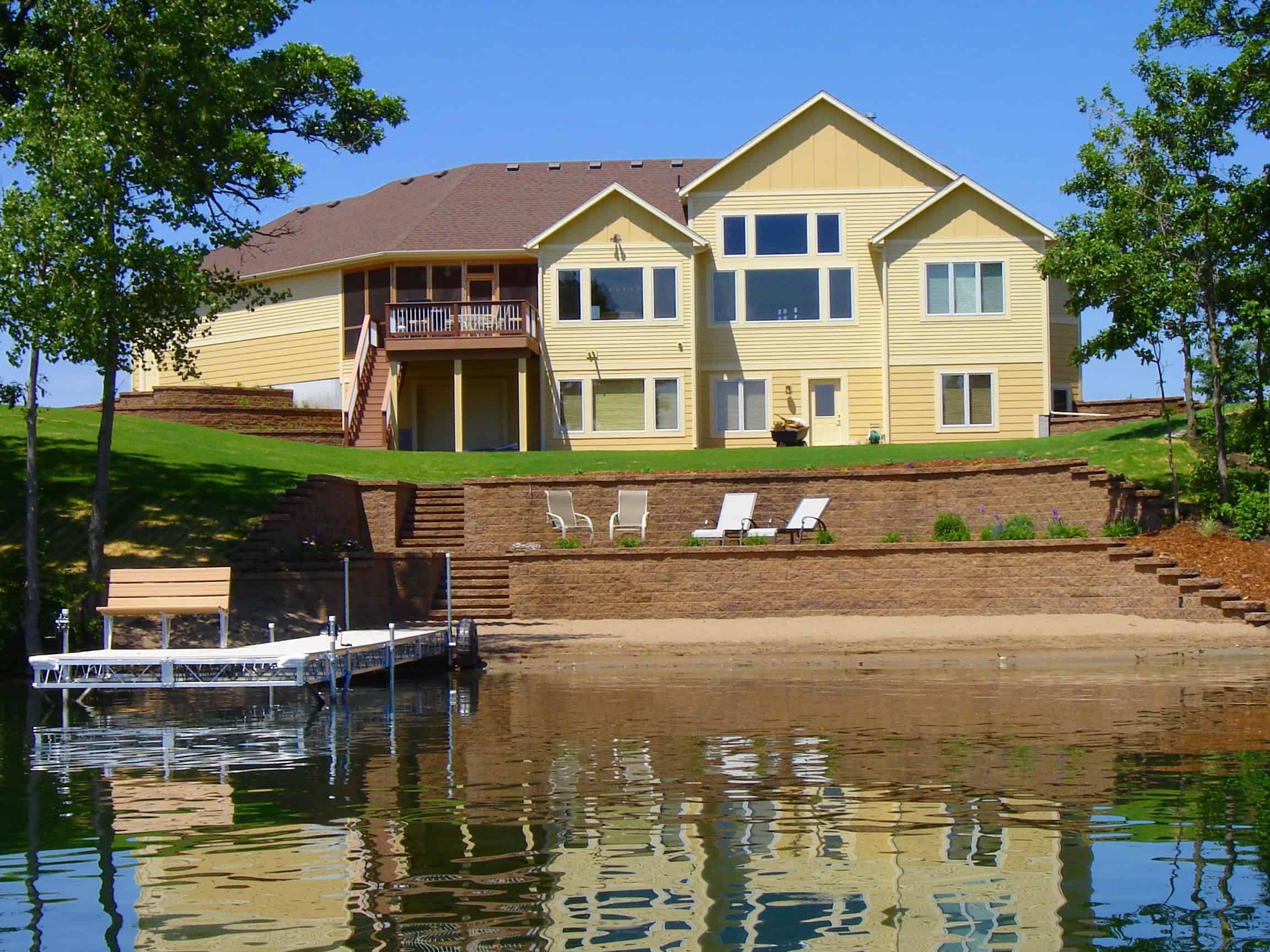 Lush green backyard with tiered landscaping and a waterfront view at a suburban home.