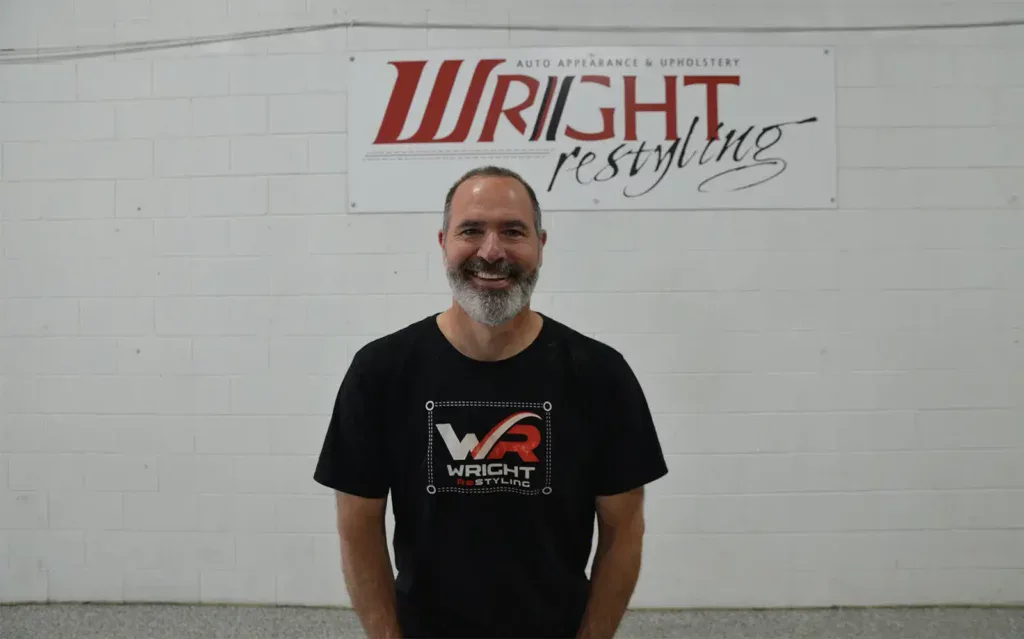 Wright ReStyling technician standing in front of company sign.