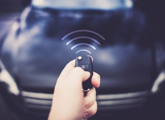 Remote car key fob with wireless signal icon, close-up shot.