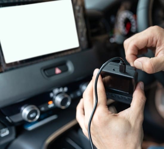 Person installing a dashcam in a car interior for recording.