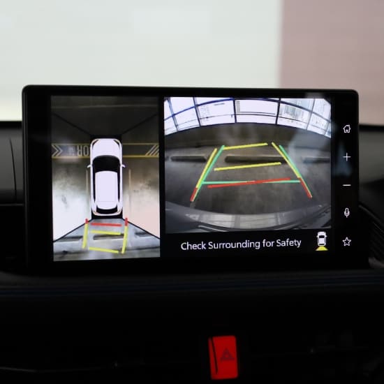Car backup camera display showing parking guidelines and surroundings.