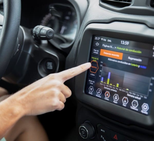 Person interacting with a digital dashboard in a vehicle interior.