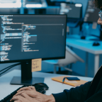 Joven programador trabajando en código en oficina tecnológica moderna.