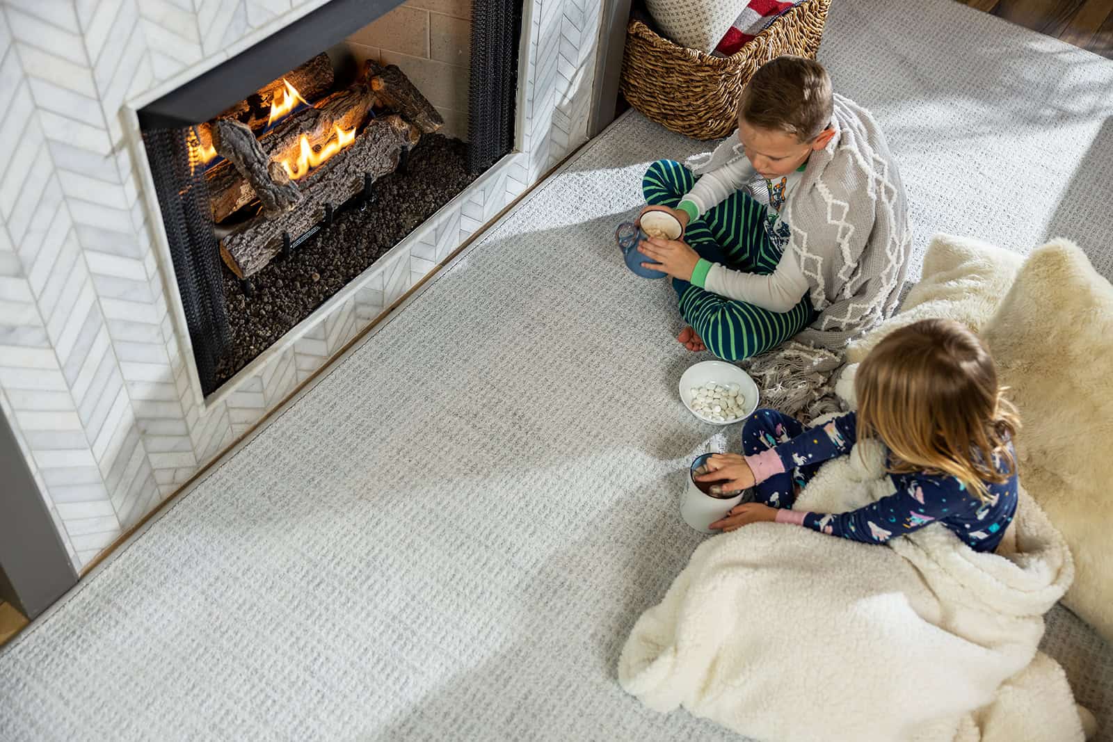 Children sitting on carpet in front of the fireplace.