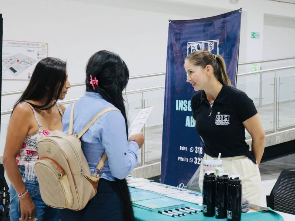 Una representante de Huila TV conversa con dos víctimas del conflicto armado en un evento de indemnización económica en Huila.