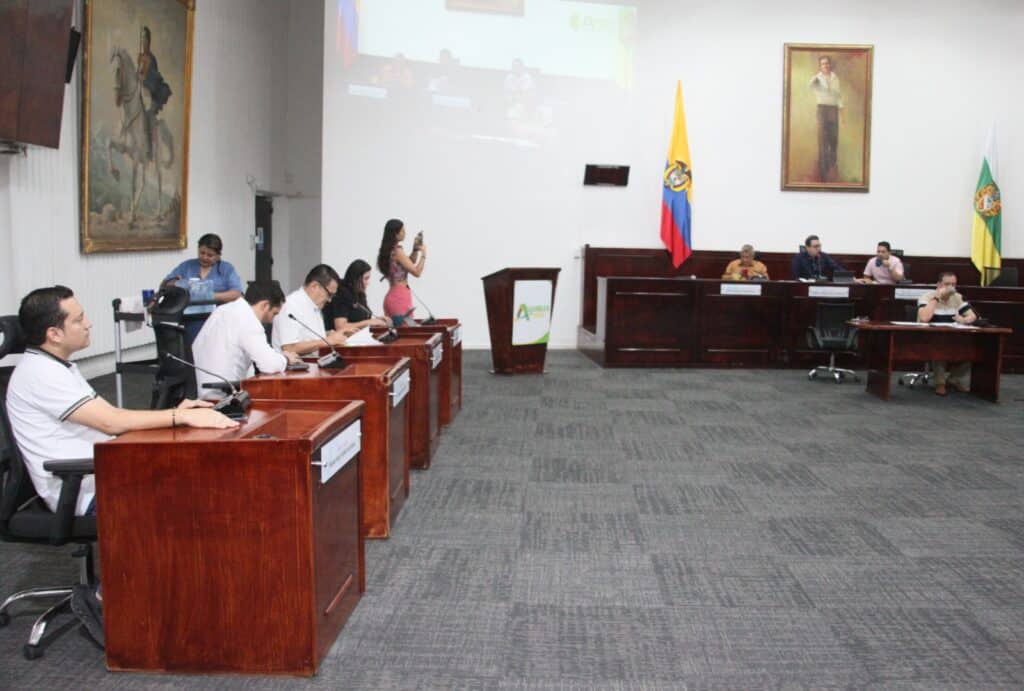 Audiencia en una sala de reuniones en Huila Tv, con bandera de Colombia y estructura de gobierno de Huila, promoviendo transparencia y participación ciudadana en eventos oficiales, con enfoque en noticias y comunicación regional.