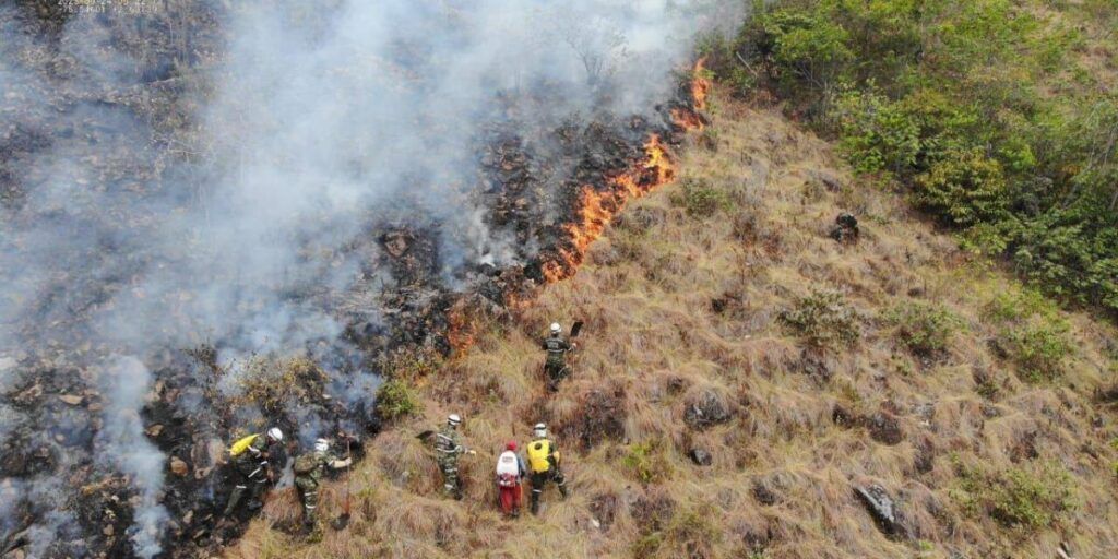 1. Incendio forestal en Huila, Colombia, con bomberos combatendo las llamas en un área rural y montañosa.