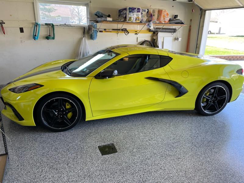 A Chevrolet Corvette is parked in a neat garage with strong J&P Coatings flooring. The space looks organized and well-maintained. Alt text: Corvette in garage with J&P Coatings floor.