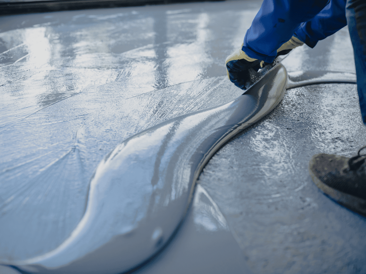 A J&P Coatings worker carefully applies fresh concrete to a floor as part of a resurfacing job.