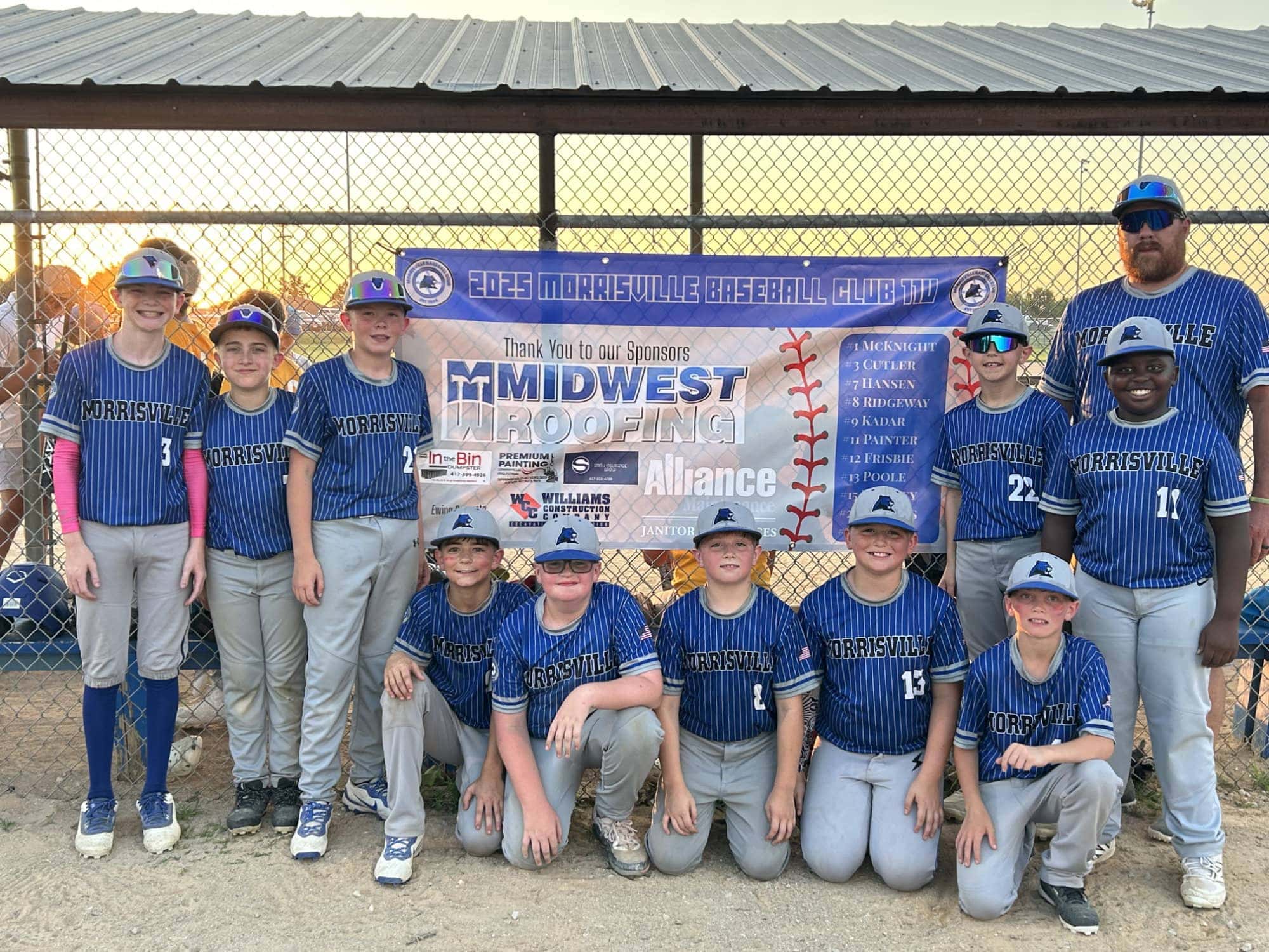 Boys in baseball uniforms pose happily together during a game or event.