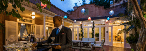A bartender in a suit crafts cocktails on 21 Royal’s lantern-lit patio at dusk, promising guests a magical Disneyland evening.