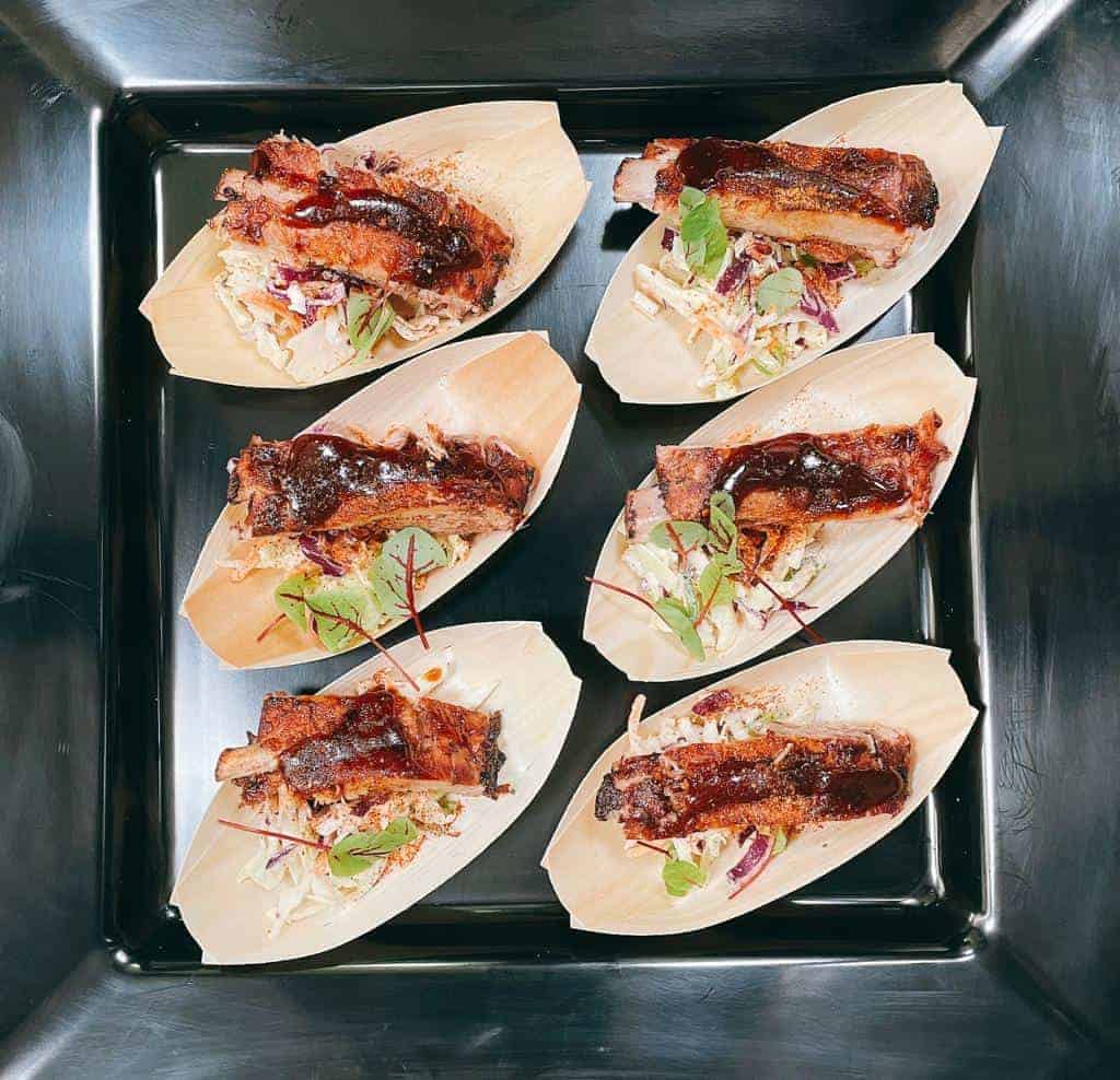 Tasty grilled meat sandwiches with fresh toppings on a black tray.