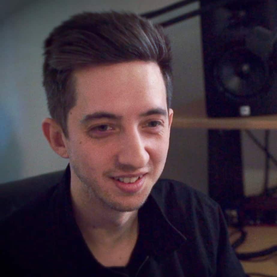 A person with short brown hair and a black shirt is smiling while seated, embodying the spirit of Generation Freedom. Audio equipment buzzes with potential in the background.
