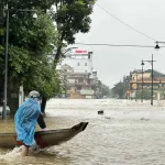 冠水した道路を船で移動するフエの市民