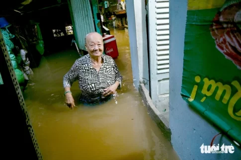 腰まで浸水した家の中を移動する老女