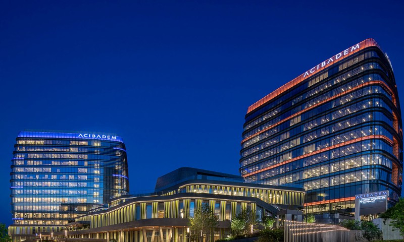 Acibadem Hospitals Group modern hospital buildings illuminated at night, showcasing advanced healthc.