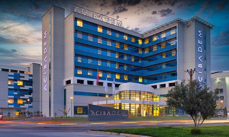 Modern Acibadem hospital building with blue and white exterior at dusk.