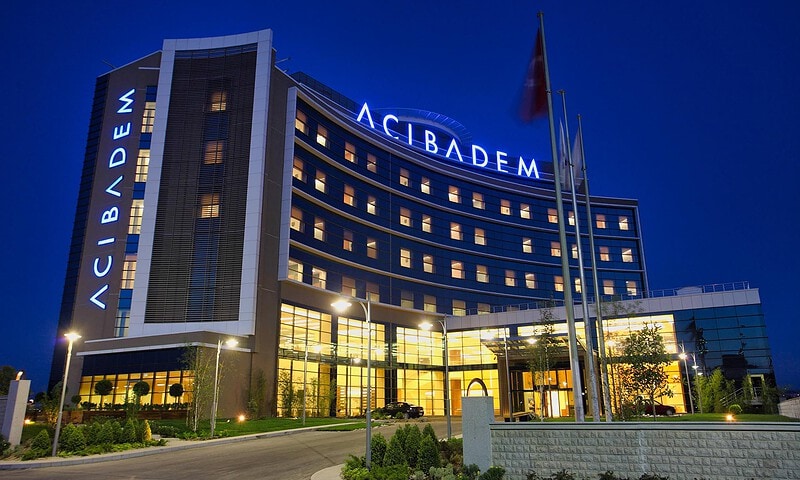 Acibadem Hospitals Group modern hospital exterior at night with illuminated signage.