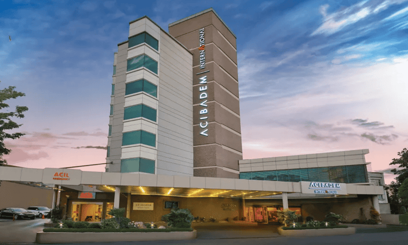 Acibadem Hospitals Group building exterior at sunset, showcasing modern healthcare facility and hosp.