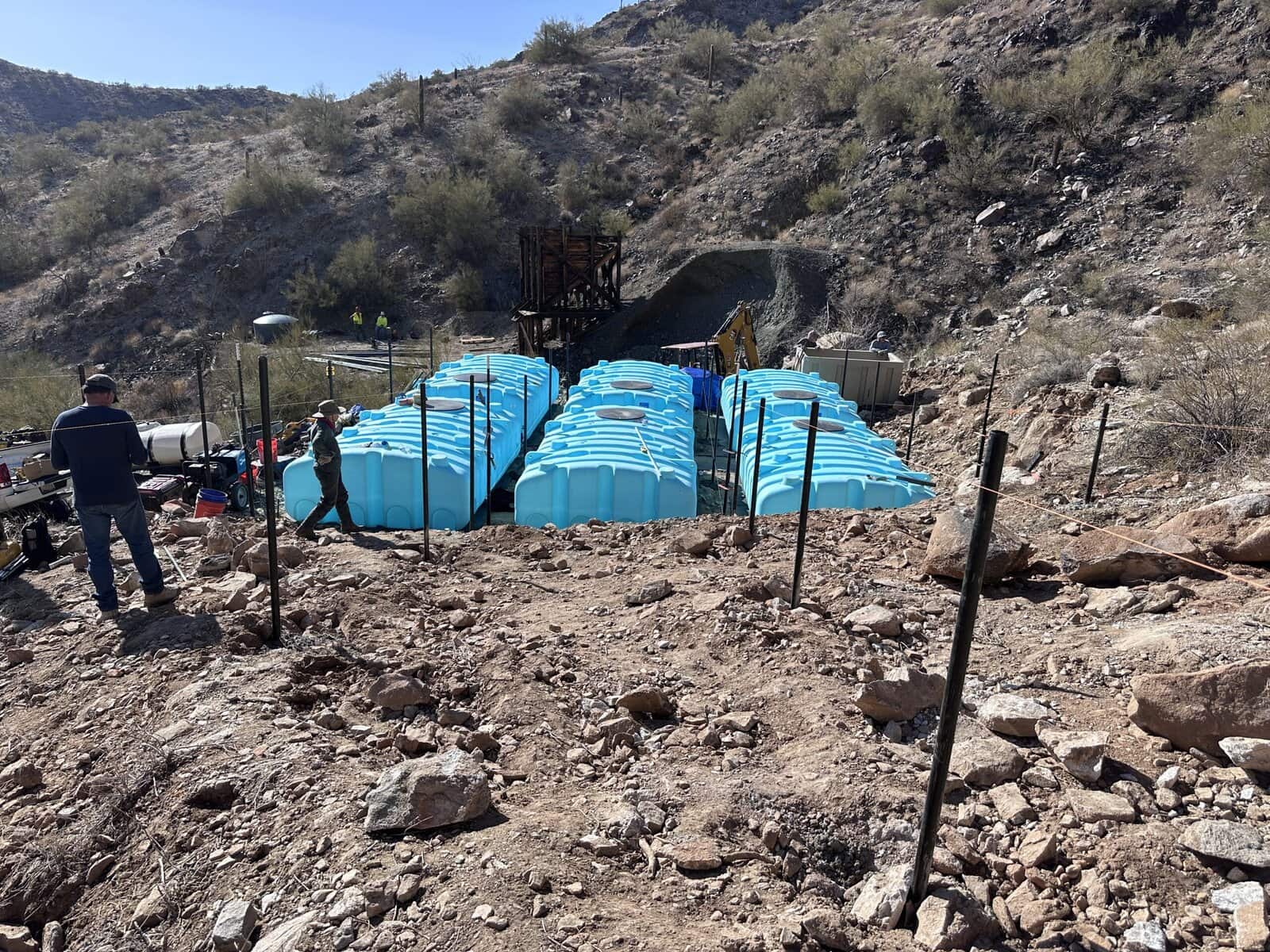 High-angle view of Arizona Desert Bighorn Sheep Society project site with water tanks, construction equipment, and staff.
