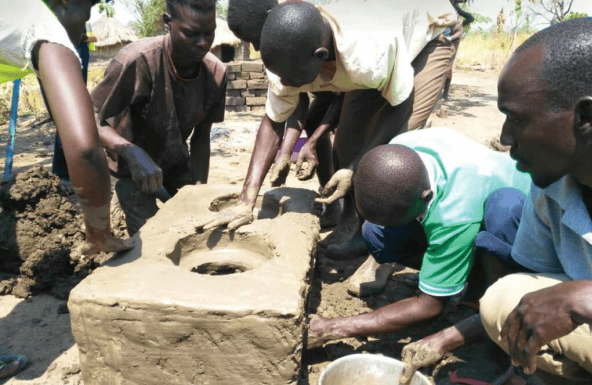 Menschen in Afrika bei der Herstellung eines Ziegels aus Lehm für nachhaltige Bauprojekte, symbolisch für Entwicklung, Bildung und lokale Gemeinschaftsarbeit – Fokus auf soziale Projekte und Bildungsförderung.