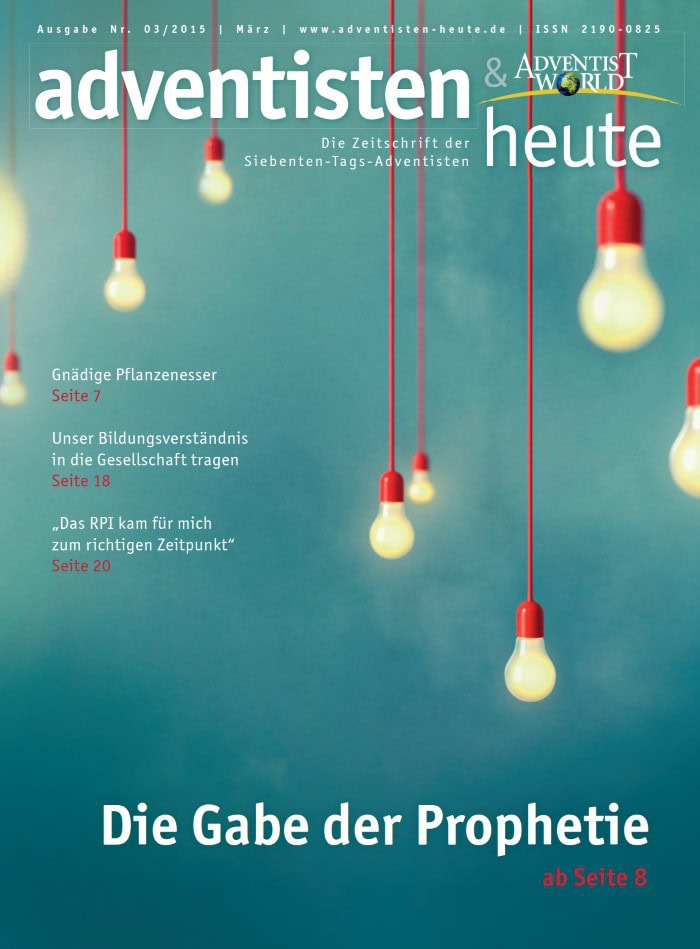 Leuchtende Glühbirnen hängen an roten Drähten vor einem blauen Hintergrund, symbolisieren Licht und Inspiration für Advents- und Weihnachtsbräuche, passend für die Zeitschrift "adventisten heute".