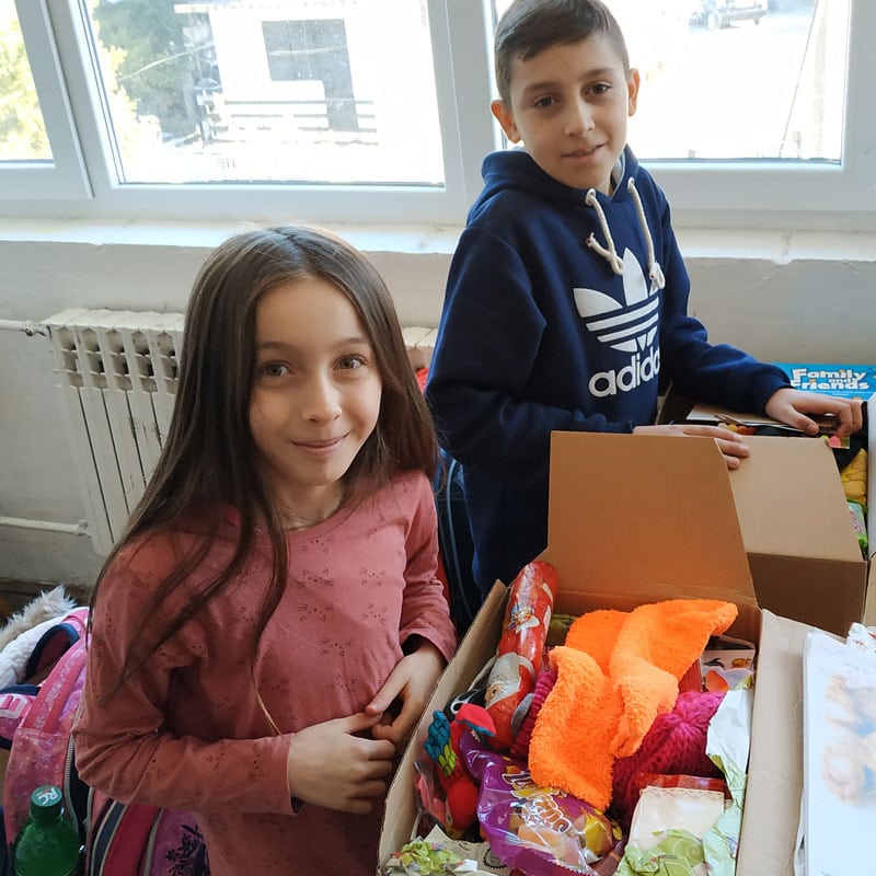 Spielzeug- und Geschenkboxen für Kinder, fröhliche Kids beim Auspacken, Spaß und Vorfreude auf besondere Anlässe, Kindergeschenke verpackt, bunte Überraschungen, Adventszeit kindgerecht, kreative Geschenkideen für Kinder.