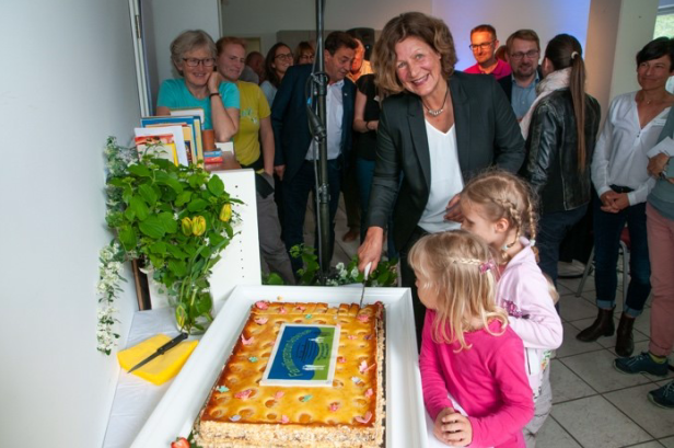 Große Feier bei Advent-Verlag mit Frau, Kindern und Gästen rund um ein Geburtstagsspießes, Symbol für Gemeinschaft, Freude und adventliche Buchvielfalt.